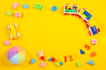 Baby kids toys background. Wooden train, car, colorful cubes and numbers on yellow background