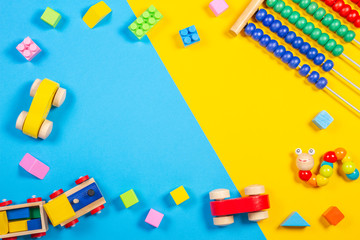 Obraz premium Baby kids toys frame with teddy bear, wooden toy train, car, colorful cubes on blue and yellow background