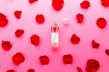 Perfume bottle with rose petals over red background