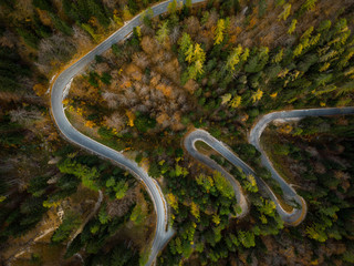 Obraz na płótnie Canvas Winding road in mountains, fall woodlands, drone view from above