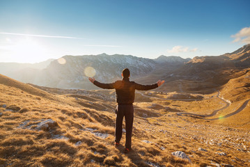Obraz premium Hiker standing on top of a hill with raised hands