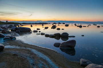 Sunset over the rocky coast of the sea. Patterns of boulders at the foreground. Baltic sea, Estonia.