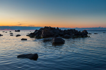 Fototapeta na wymiar Sunset over the rocky coast of the sea. Patterns of boulders at the foreground. Baltic sea, Estonia.