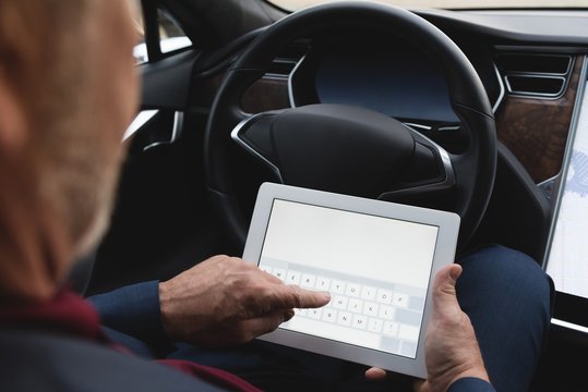 Businessman using digital tablet in a car