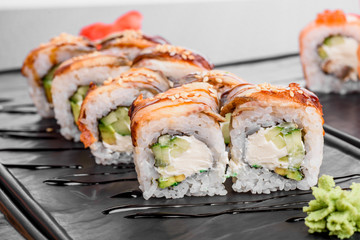 Maki Sushi set on dark pattern background. Sushi Set nigiri, rolls and sashimi served in black square plate