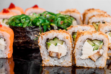 Maki Sushi set on dark pattern background. Sushi Set nigiri, rolls and sashimi served in black square plate