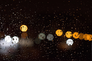 Street lights bokeh through a rain splattered window