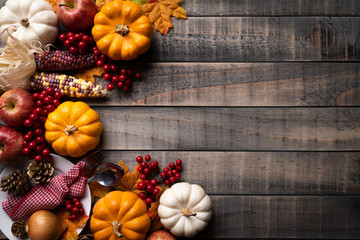 Top view of  Autumn maple leaves with Pumpkin, apple, corn and red berries on old wooden background. Thanksgiving day concept.