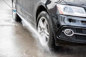 Close-up of a car under the water jet during the washing process on a self service car wash