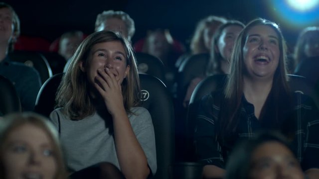 Female friends laughing and having fun at the movie theatre