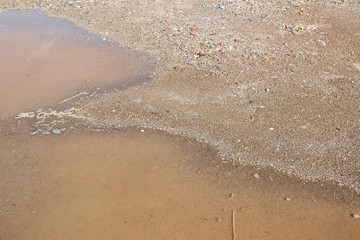 Muddy puddle on beige brown dirt road abstract horizontal
