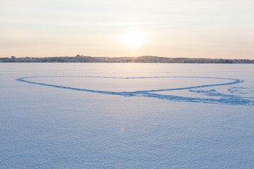 Heart shape made in snow by walking at frozen lake