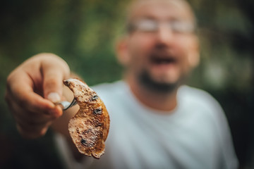 Man with open mouth showing you meat from the grill, outdoor barbecue, copy space
