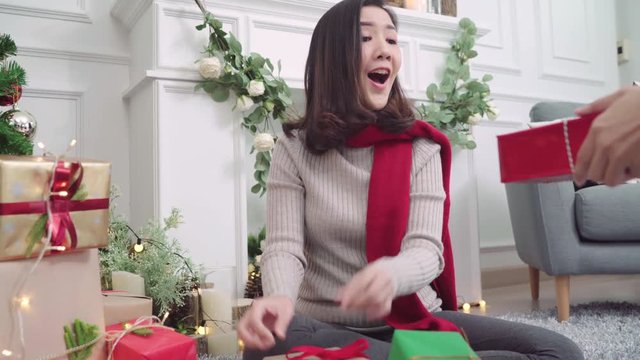 Lesbian Asian couple giving christmas gifts to each other in her living room at home in Christmas Festival. Lifestyle lgbt women happy celebrate Christmas and New year concept.