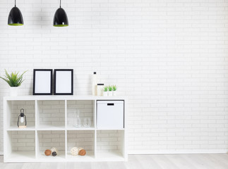Modern loft interior with white brickwall, lamp, shelf, pictures, plants and some decoration