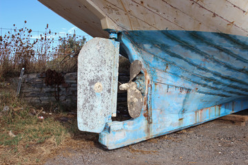 Rudder and propeller of old abandoned fishing sea ship boat on land landscape