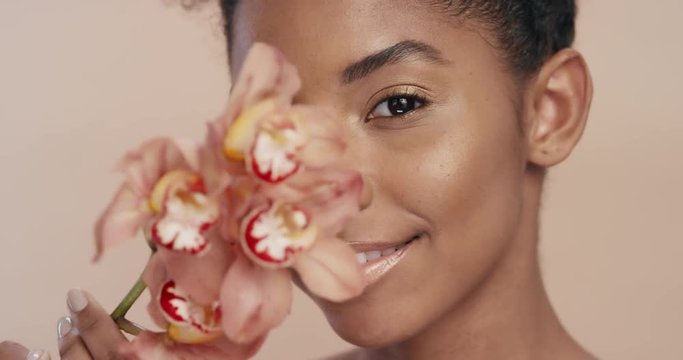 beauty portrait beautiful african american woman playfully posing with orchid flower touching healthy skin complexion enjoying gentle fragrance of natural essence skincare concept