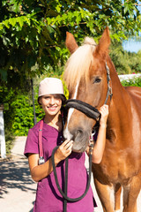 Portrait of young female equestrian veterinarian with brown horse at an animal park.