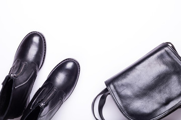 Woman accessory. Black stylish boots, black luxury leather bag on white background. Top view background. Flat lay. Copy space.