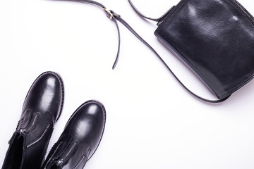 Woman accessory. Black stylish boots, black luxury leather bag on white background. Top view background. Flat lay. Copy space.