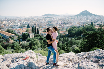 couple have a date on the peak of the hill with panorama view on the city kissing each other