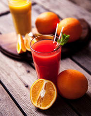 Orange juice in glass with mint, fresh fruits on wooden background