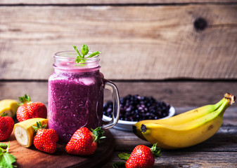 Blueberry smoothies on a wooden background with fruits. Vitamins