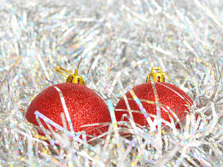 Two red Christmas balls and shiny tinsel of silver color, concept of holidays, Christmas and New Year, close up