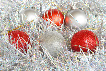 Red and silver Christmas balls and shiny tinsel of silver color, background and concept of holidays, Christmas and New Year, close up