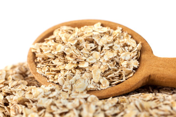 Heap of rolled oats with wooden spoon on white