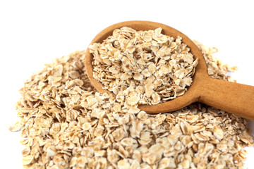 Heap of rolled oats with wooden spoon on white
