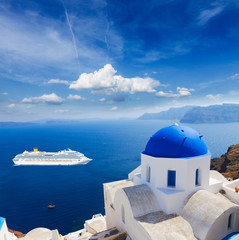 traditional blue dome of church and blue sea water with cruise ship, Oia, Santorini island, Greece