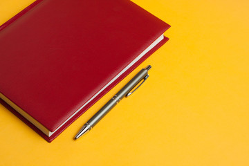 concept business time is money, a new beautiful red notebook and pen for responsible people on a bright yellow background