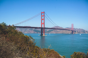 Classic panoramic view of famous Golden Gate Bridge seen from Baker Beach in beautiful summer sunny day with blue sky, San Francisco, California, USA