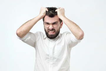 Angry spanish man pulling out his hair, being mad looking with furious expression
