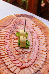 Delicious slices of pork dried meat decorated in circles on large plate. Large plate with meat slices on a wedding