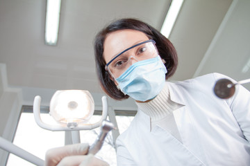 Doctor dentist in mask looks at patient