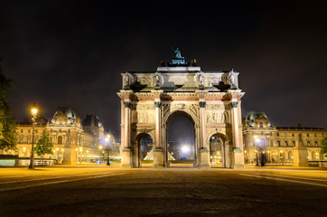 Triumphal Arch (Arc de Carrousel) and Louvre museum at background at night in Paris, France