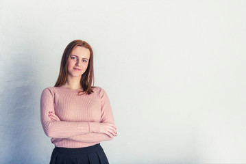 Obraz premium piękna młoda poważna kobieta skrzyżowała ramiona na szarym tle, beżowa tonacja, miejsce na copyspace