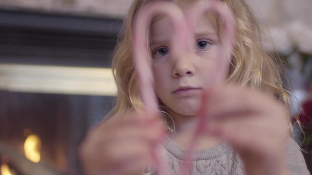Little Girl Concentrates Trying To Make The Perfect Heart Shape With 2 Candy Canes, She Realizes She Did It And Smiles Wide
