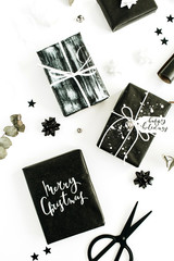 Black homemade gift boxes and decorations on white background. Merry Christmas, Happy holidays. Flat lay, top view festive composition.