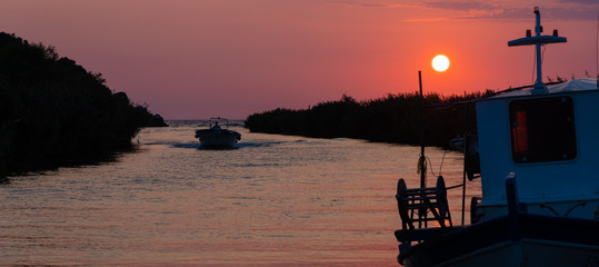 A boat entering the harbor during sunset