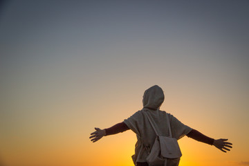 Fototapeta premium silueta de una mujer viajera con mochila a contraluz en un amanecer o atardecer