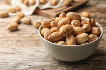 Pecan nuts in bowl on wooden table, space for text