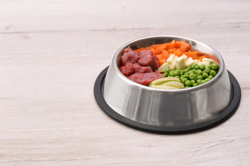Bowl with organic dog food on light background. Space for text