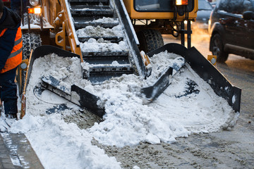 Snow-removal machine cleans the street of snow. Workers sweep snow from road in winter, Cleaning...