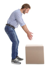 Full length portrait of young man lifting heavy cardboard box on white background. Posture concept
