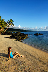 Young woman sitting on a beach in Lavena village on Taveuni Island, Fiji