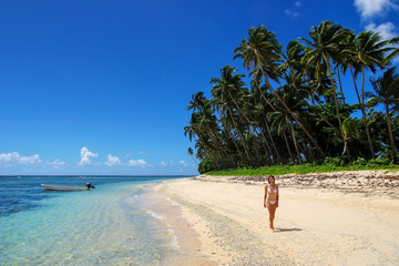 Young woman in bikini walking on a beach in Lavena village on Taveuni Island, Fiji