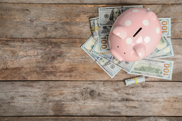 Piggy bank with money and space for text on wooden background, top view